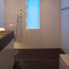 Der Raum zeigt eine stilvolle Badewanne, eine Dusche mit Glaswand und eine minimalistische Einrichtung in sanften Farben.