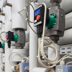 Technische Ausrüstung mit Rohren, Ventilen und Steuergeräten, die in einem industriellen Umfeld angeordnet sind.