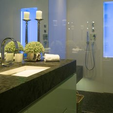 Ein modernes Badezimmer mit einem eleganten Waschbecken aus schwarzem Stein und stilvollen Pflanzen auf der Ablage.