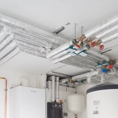 Die Decke zeigt ein Netzwerk von silbernen Rohren und Ventilen, die für Heizungs- oder Wasserversorgungssysteme verwendet werden.