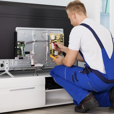 Ein Elektroniker der einen Fernseher repariert in einem Wohnzimmer