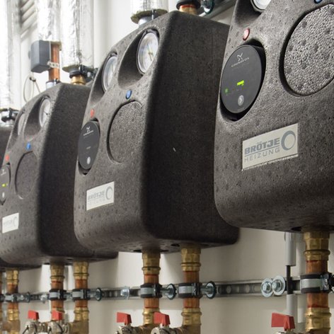 Die Installation zeigt mehrere Heizungsregler mit digitalen Anzeigen und farbigen Tasten, die an einer Wand befestigt sind.